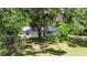 Quaint single-story home featuring a metal roof, light-colored siding and a large, mature tree at 12434 Cody Dr, Wimauma, FL 33598