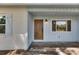 Inviting front entrance with wood door, sidelight window, fresh paint, and classic exterior lighting at 12434 Cody Dr, Wimauma, FL 33598