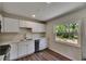 Bright kitchen features modern white cabinets, stainless steel appliances, and a view of the lush backyard at 12434 Cody Dr, Wimauma, FL 33598