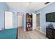 Comfortable bedroom featuring light wood floors, light blue walls, a TV, and plenty of natural light at 12648 Castle Hill Dr, Tampa, FL 33624