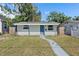 Charming single-story home with a blue front door, solar panels, and freshly painted siding at 1310 43Rd S St, St Petersburg, FL 33711
