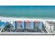 Exterior view of a beachfront condo building with vibrant colors, palm trees, and convenient parking at 13720 Gulf Blvd # 302, Madeira Beach, FL 33708
