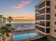 Exterior view of a beachfront building with a pool and ocean sunset at 13720 Gulf Blvd # 302, Madeira Beach, FL 33708