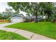 Single-story home with green lawn, mature tree, front flower beds, and two-car garage at 14902 Foxhound Pl, Tampa, FL 33624