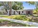 Inviting single-story house with green lawn, mature trees, and a brick accent wall at 1708 Julian Lane Dr, Tampa, FL 33619