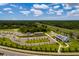 Community aerial view showcasing a modern building, green spaces, gardens, and ample parking under a bright, partly cloudy sky at 17263 Mango Shay Ct, Land O Lakes, FL 34638