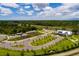 An aerial view of a well-maintained community farm with garden plots, a greenhouse, parking, and a charming farmhouse-style building at 17263 Mango Shay Ct, Land O Lakes, FL 34638