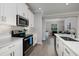 Well-lit kitchen boasts stainless steel appliances, white cabinets, quartz counters, and tile floors at 17263 Mango Shay Ct, Land O Lakes, FL 34638