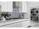 Modern kitchen features sleek white cabinetry, stainless steel appliances, a designer backsplash, and granite countertops at 199 Dali Blvd # 2, St Petersburg, FL 33701