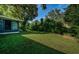 A well-manicured backyard with green grass, mature trees and sunroom extension at 209 S Greenfield Ave, Temple Terrace, FL 33617