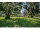 The property features a wide expanse of lush green grass shaded by mature trees at 209 S Greenfield Ave, Temple Terrace, FL 33617