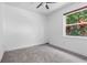 A clean, carpeted bedroom featuring a window view with natural light and tropical foliage at 2498 Saddlewood Ln, Palm Harbor, FL 34685