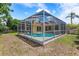 Spacious backyard with a screened-in pool and lush tropical landscaping at 2498 Saddlewood Ln, Palm Harbor, FL 34685
