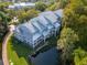 Aerial view of a multi-story condo building with a metal roof, surrounded by trees and a pond with wooden walkway at 2533 Dolly Bay Dr # 203, Palm Harbor, FL 34684