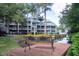 Scenic view of a multi-story condo building overlooking a tranquil canal with lush landscaping and a relaxing dockside bench at 2533 Dolly Bay Dr # 203, Palm Harbor, FL 34684