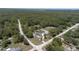 An aerial view showcases the home nestled on a lot surrounded by lush trees, close to a road, and a short distance from town at 27709 Robin Roost Ln, Wesley Chapel, FL 33544