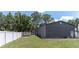 View of the side of a detached garage in a fenced back yard, with lush trees at 27709 Robin Roost Ln, Wesley Chapel, FL 33544