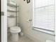 Bright bathroom featuring a toilet, shelving unit, and a window with natural light at 27709 Robin Roost Ln, Wesley Chapel, FL 33544