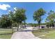 Attractive single-Gathering home featuring a long driveway, a well-manicured lawn, and mature landscaping with palm trees at 27709 Robin Roost Ln, Wesley Chapel, FL 33544