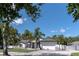 Charming home with a two-car garage, landscaped yard, palm trees, modern exterior paint, and a white fence at 27709 Robin Roost Ln, Wesley Chapel, FL 33544