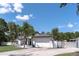 Beautiful home with a two-car garage, well-manicured lawn, palm trees, modern exterior paint, and a white fence at 27709 Robin Roost Ln, Wesley Chapel, FL 33544
