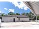 Exterior of house and large garage on green grass lawn, divided by white picket fence at 27709 Robin Roost Ln, Wesley Chapel, FL 33544