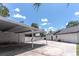 View of the garage, carport, and back of the house with a white picket fence on a sunny day at 27709 Robin Roost Ln, Wesley Chapel, FL 33544