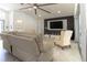 Bright living room featuring a modern ceiling fan, a stylish entertainment center and sliding glass doors at 27709 Robin Roost Ln, Wesley Chapel, FL 33544