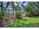 Lush backyard with green grass and tropical plants offers a private oasis and serene retreat at 3002 Savannah Oaks Cir, Tarpon Springs, FL 34688