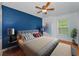 Bedroom features include a blue accent wall, ceiling fan, wood-look flooring, and comfortable bed at 3002 Savannah Oaks Cir, Tarpon Springs, FL 34688
