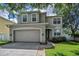 Two story home showcasing a well-manicured lawn, neutral color scheme, attached two car garage and trimmed windows at 3002 Savannah Oaks Cir, Tarpon Springs, FL 34688