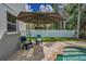 Inviting pool patio featuring an umbrella and comfortable seating with chairs, perfect for relaxation at 3002 Savannah Oaks Cir, Tarpon Springs, FL 34688