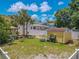 A spacious backyard with a yellow shed, a tiki bar, green grass, and a white privacy fence at 316 Lafayette Blvd, Oldsmar, FL 34677