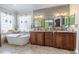 Elegant bathroom featuring a soaking tub, custom cabinetry, double sinks, and stylish mirrors at 316 Lafayette Blvd, Oldsmar, FL 34677