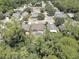 Aerial view of a neighborhood showcasing a home with a screened pool in a lush, tree-lined community at 3338 Laurelwood Ct, Tarpon Springs, FL 34688