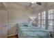 Cozy bedroom featuring a ceiling fan, shuttered windows, and a comfortable bed with a decorative teal comforter at 3338 Laurelwood Ct, Tarpon Springs, FL 34688