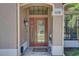 Elegant front entry with a decorative glass door, tiled porch, and stylish exterior lighting at 3338 Laurelwood Ct, Tarpon Springs, FL 34688