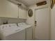 Functional laundry room with washer, dryer, overhead cabinets, and a convenient exterior door at 3338 Laurelwood Ct, Tarpon Springs, FL 34688