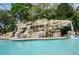 Beautiful waterfall feature cascading into the community pool with surrounding rock formations and landscaping at 36750 Us 19 N # 24-211, Palm Harbor, FL 34684