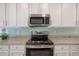Close-up of kitchen with modern stove, white cabinets, granite countertops, and tile backsplash at 3906 N Lynn Ave, Tampa, FL 33603