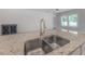 Kitchen island with a stainless steel sink, granite countertops, and a view of the adjacent room at 3906 N Lynn Ave, Tampa, FL 33603