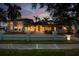 Elegant two-story home with a well-manicured lawn, black metal fence, and beautiful front entrance at dusk at 405 S Shore Crest Dr, Tampa, FL 33609