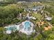 Aerial view of community with clubhouse, pools, playground, open fields and tree lined streets near retention pond at 4264 Bexley Village Dr, Land O Lakes, FL 34638