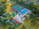 Aerial view of community courts with tennis courts, a pool, a hot tub, a tennis court and lush landscaping at 455 Cypress Lake Ct, Oldsmar, FL 34677