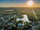 Stunning aerial view of the community featuring a lake, pool, and tennis courts amidst lush greenery at sunset at 455 Cypress Lake Ct, Oldsmar, FL 34677