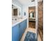 Bright bathroom featuring blue vanity, illuminated mirror, and tiled shower with a bedroom view at 455 Cypress Lake Ct, Oldsmar, FL 34677