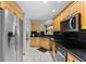 Well-lit kitchen featuring stainless steel appliances, black countertops, and light wood cabinets at 5032 Cypress Trace Dr, Tampa, FL 33624