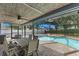 Relaxing screened-in outdoor dining area with a beautiful pool and lush landscaping at 5032 Cypress Trace Dr, Tampa, FL 33624