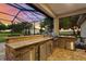 Screened outdoor kitchen with stone counter and stainless steel grill at 5319 W Trapnell Rd, Dover, FL 33527
