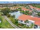 Aerial view capturing a waterfront community with vibrant landscaping, a serene lake, and residential buildings with tile roofs at 6131 Bahia Del Mar Blvd # 241, St Petersburg, FL 33715
